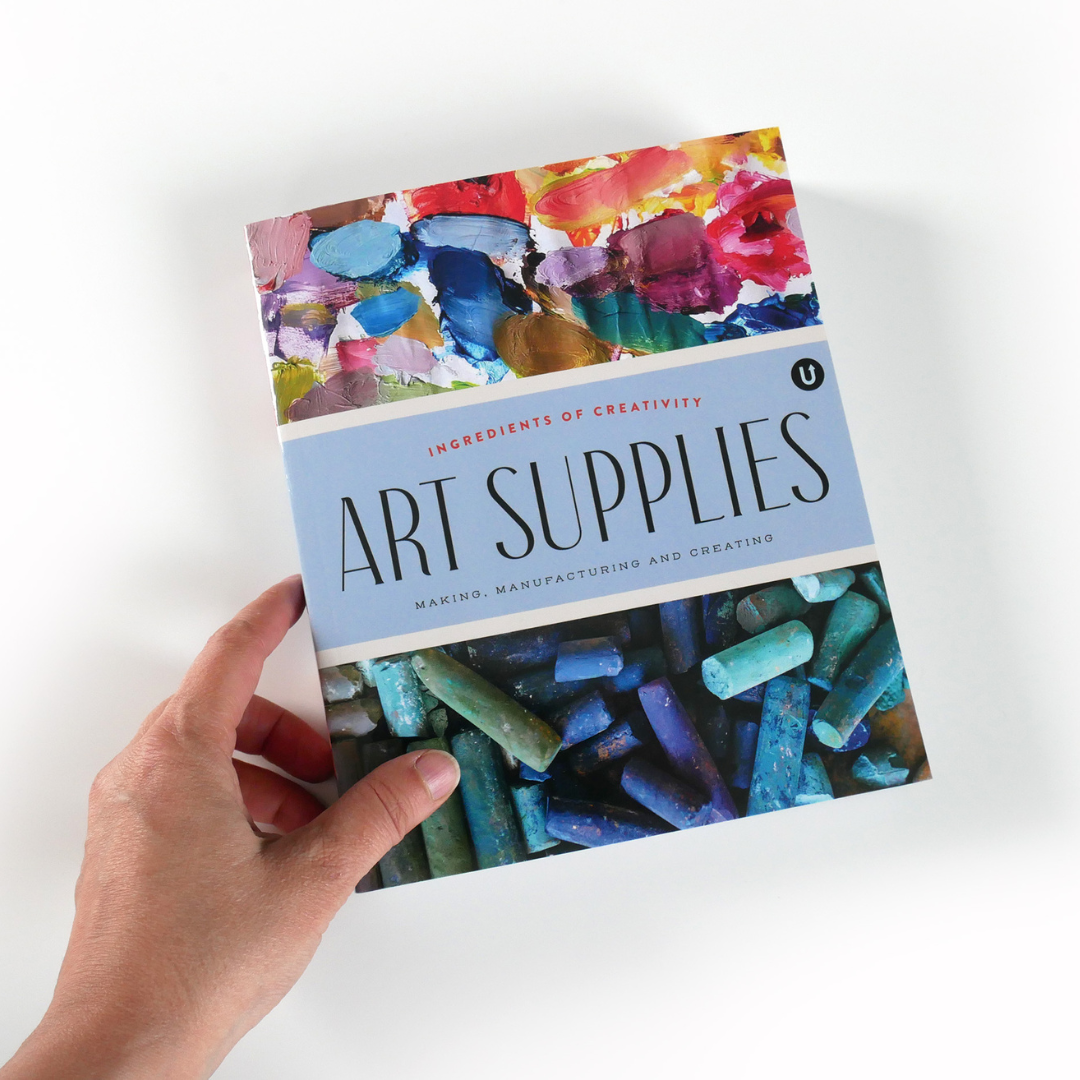 Person's hand holding the "Art Supplies" book on a white background