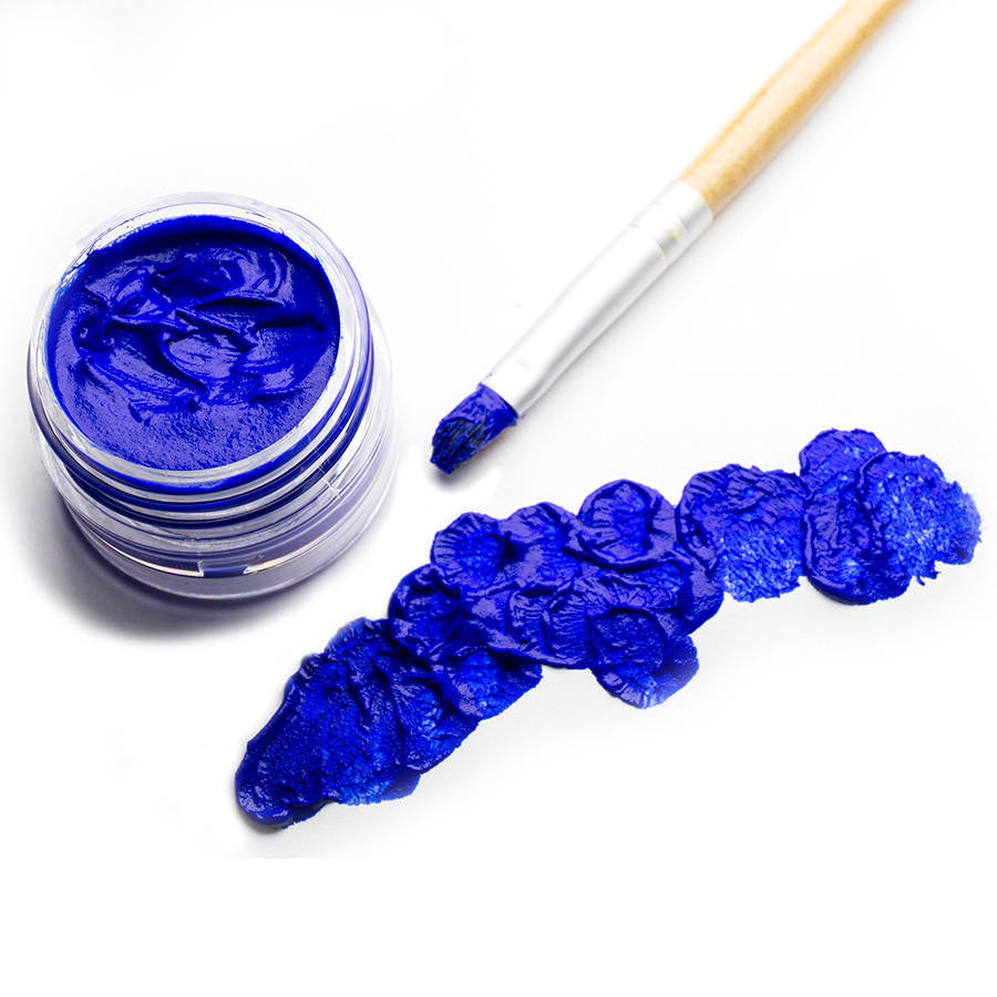 An open jar of blue face paint with brush and daubs of blue paint on white paper