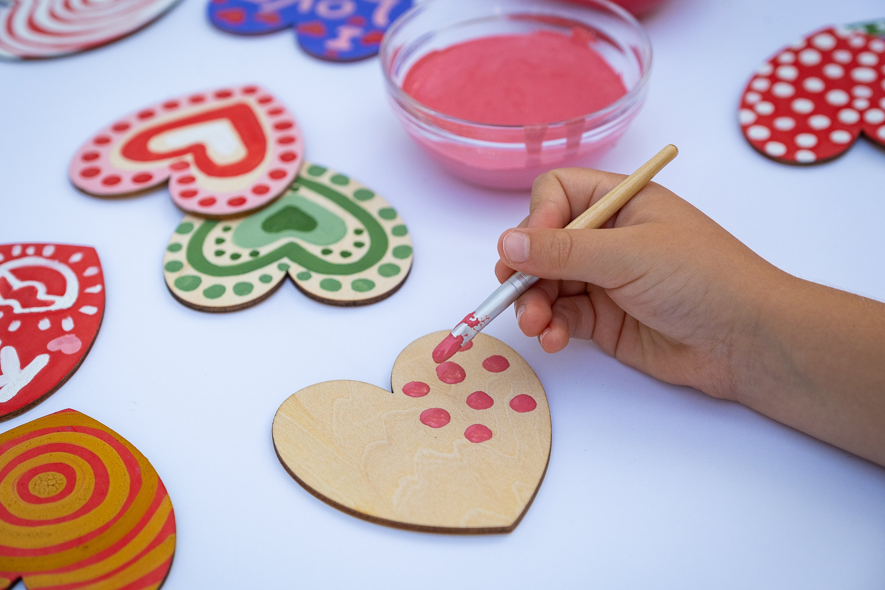 child painting wooden hearts