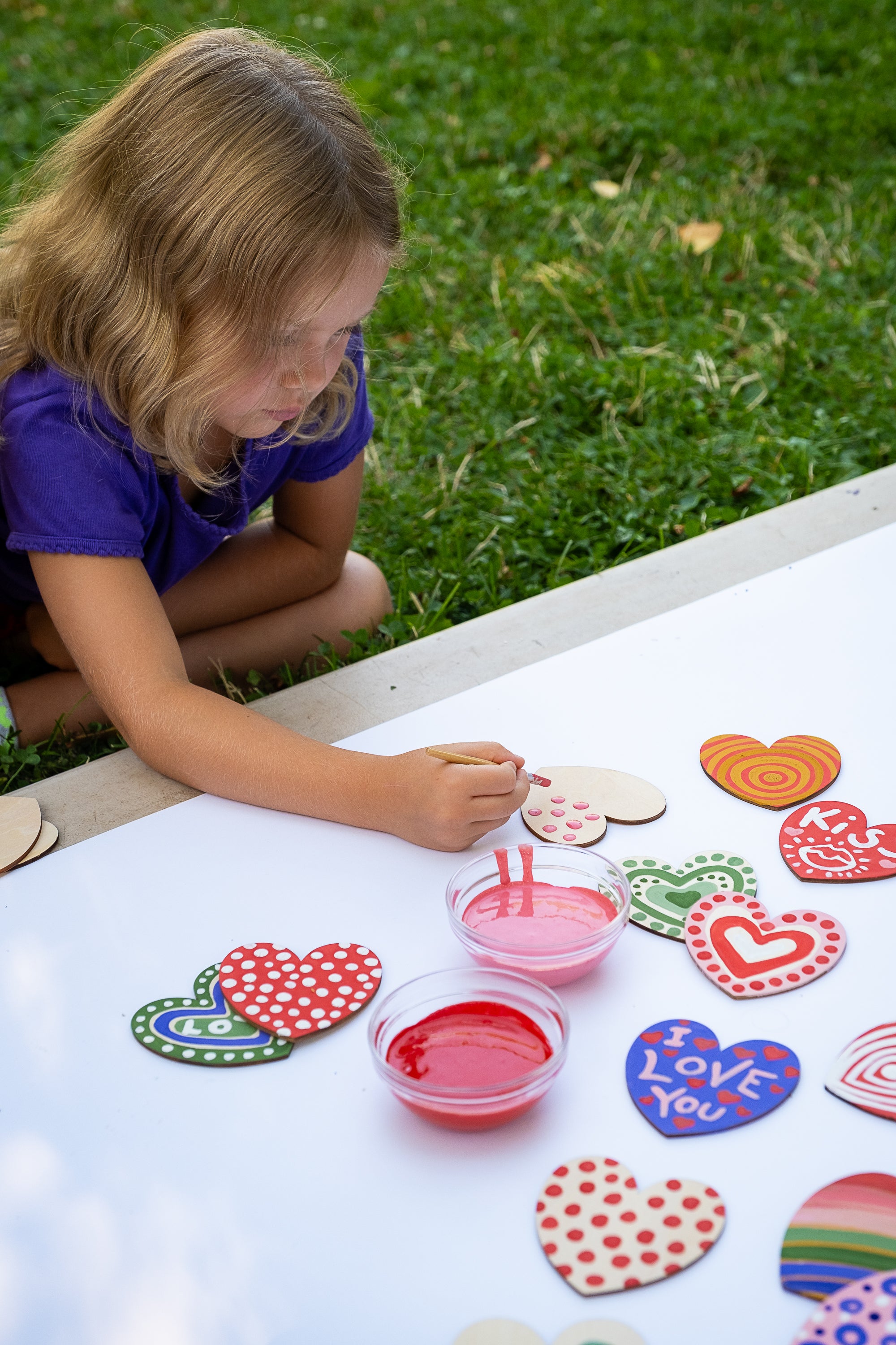 child painting wooden hearts for valentines day