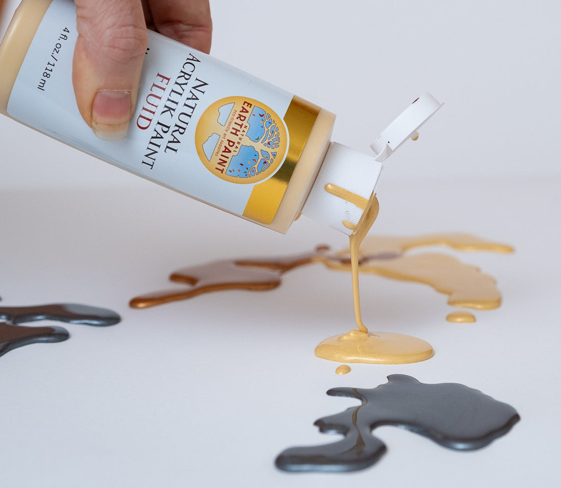 hand putting gold fluid acrylic paint on pallet