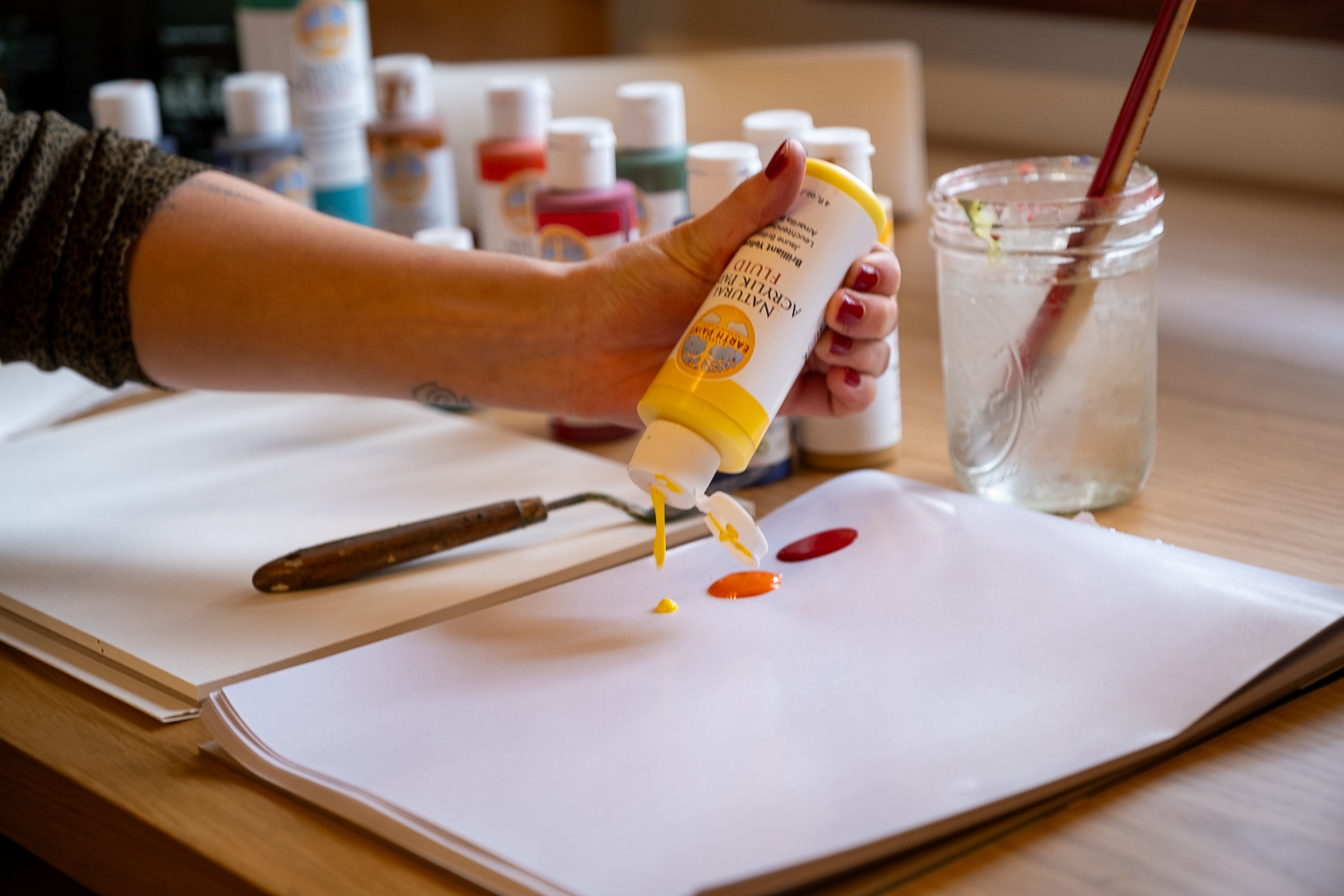 hand putting yellow natural acrylic paint on pallet