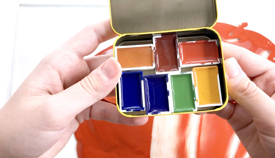 hand holding container of a variety of watercolors