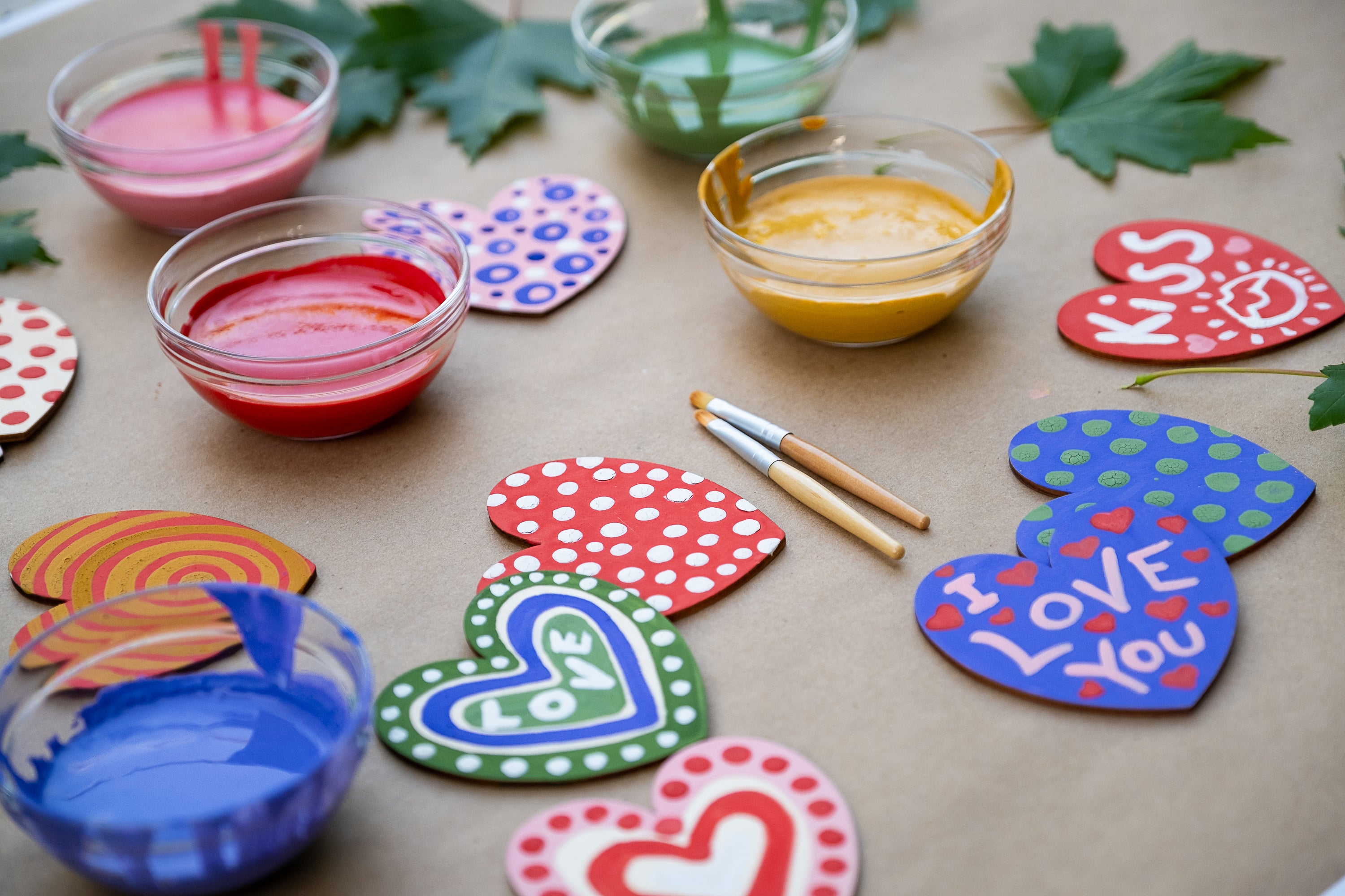 painted wooden hearts with bowls of paint and brushes