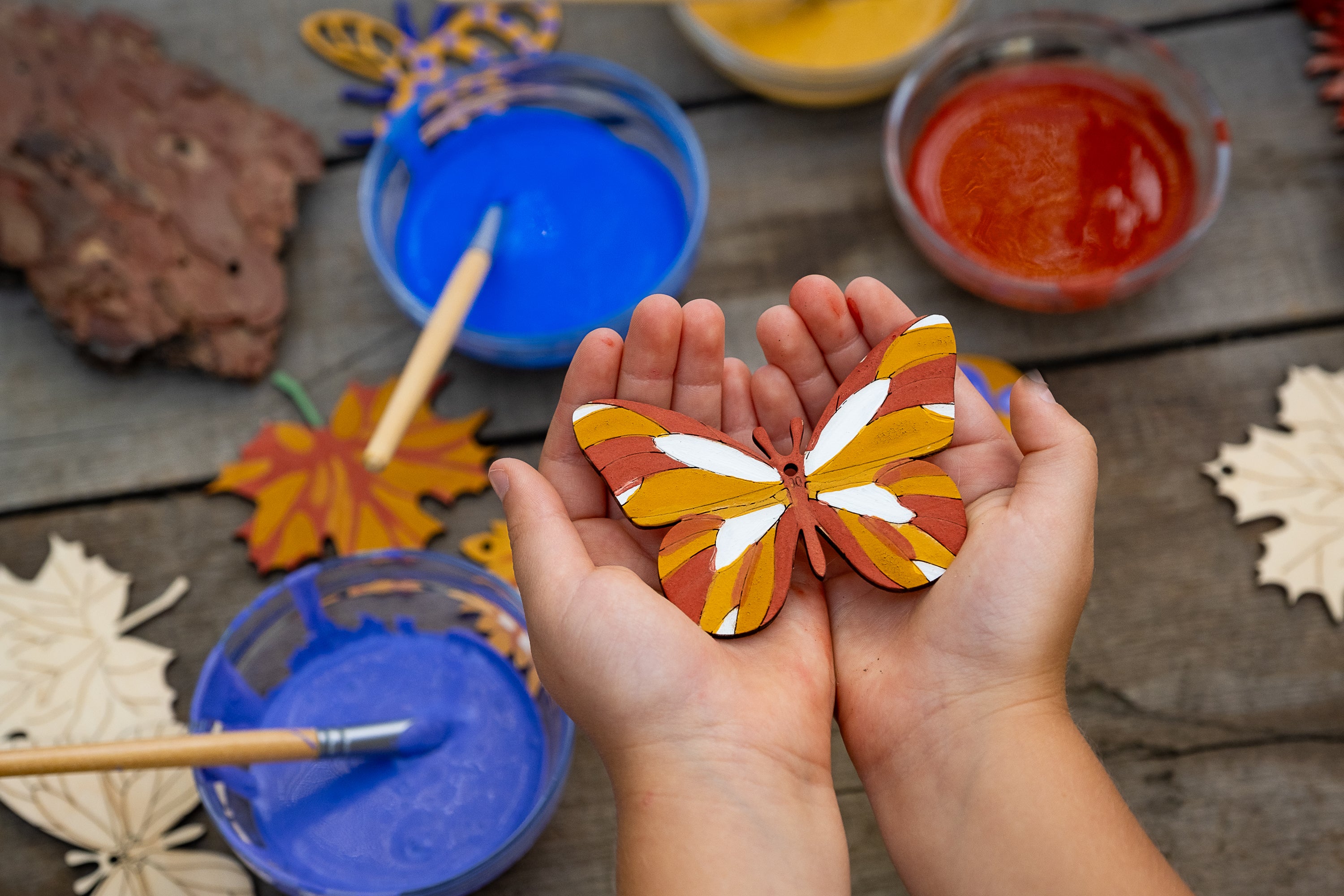 Child holding a painted wooden butterfly