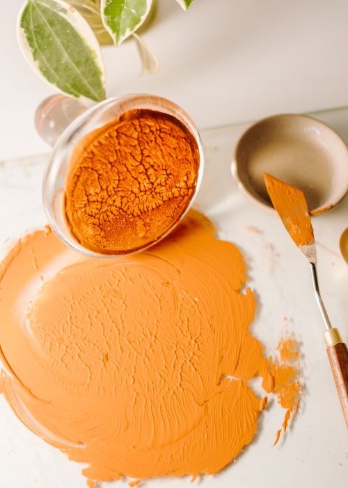 orange oil paint on pallet with muller and pallet knife
