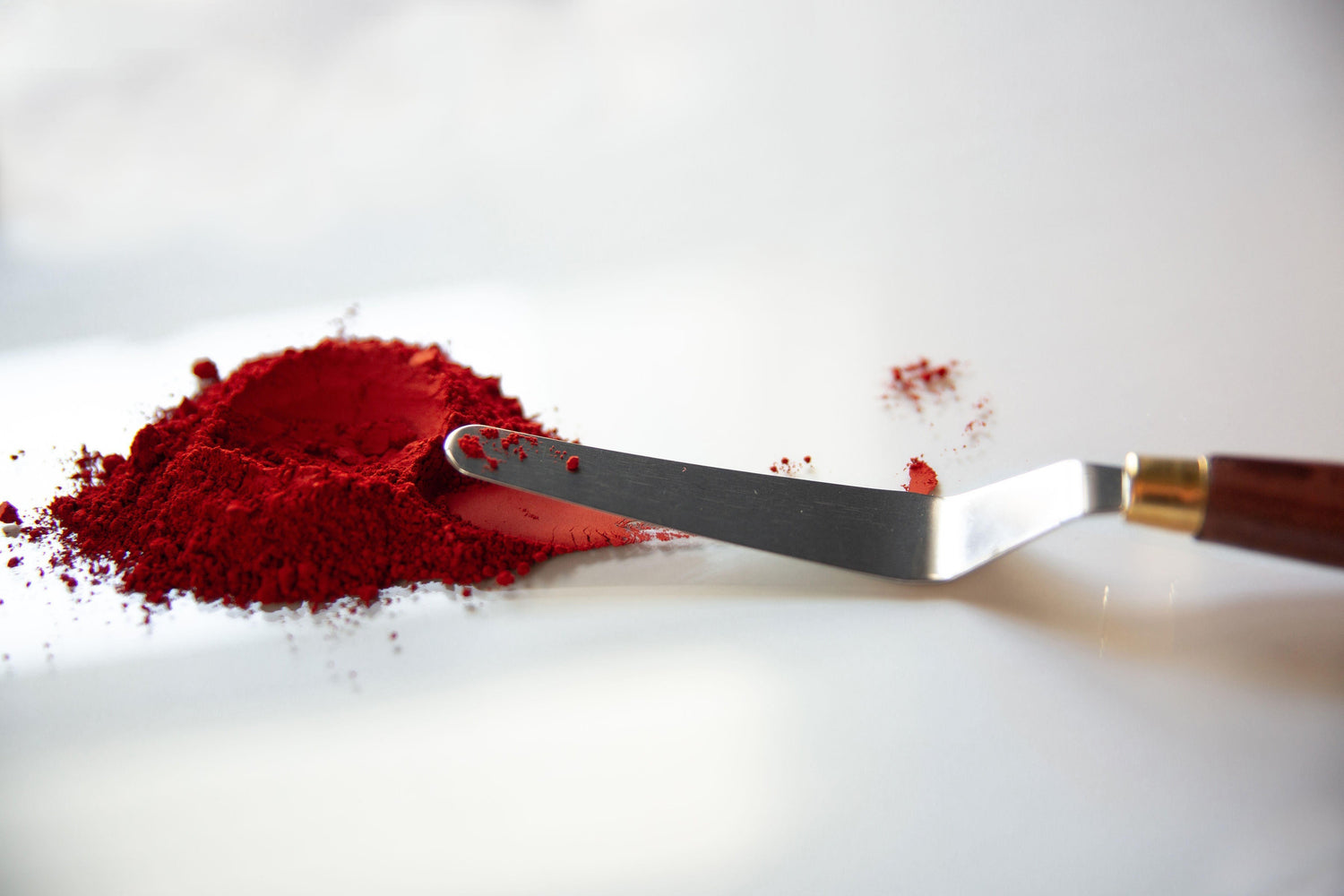 Pile of red earth & mineral pigment sitting on a glass palette next to a palette knife