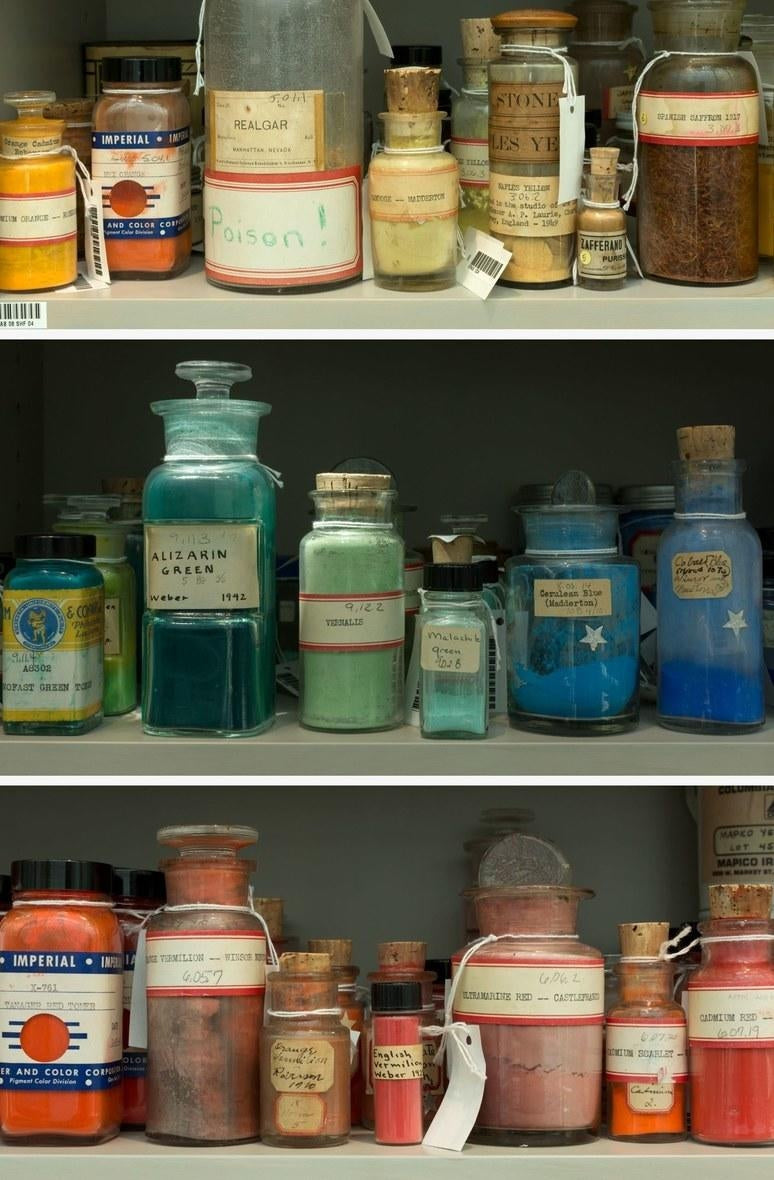 Shelf holding a diverse collection of a full rainbow of pigments in glass jars and bottle in various shapes and sizes