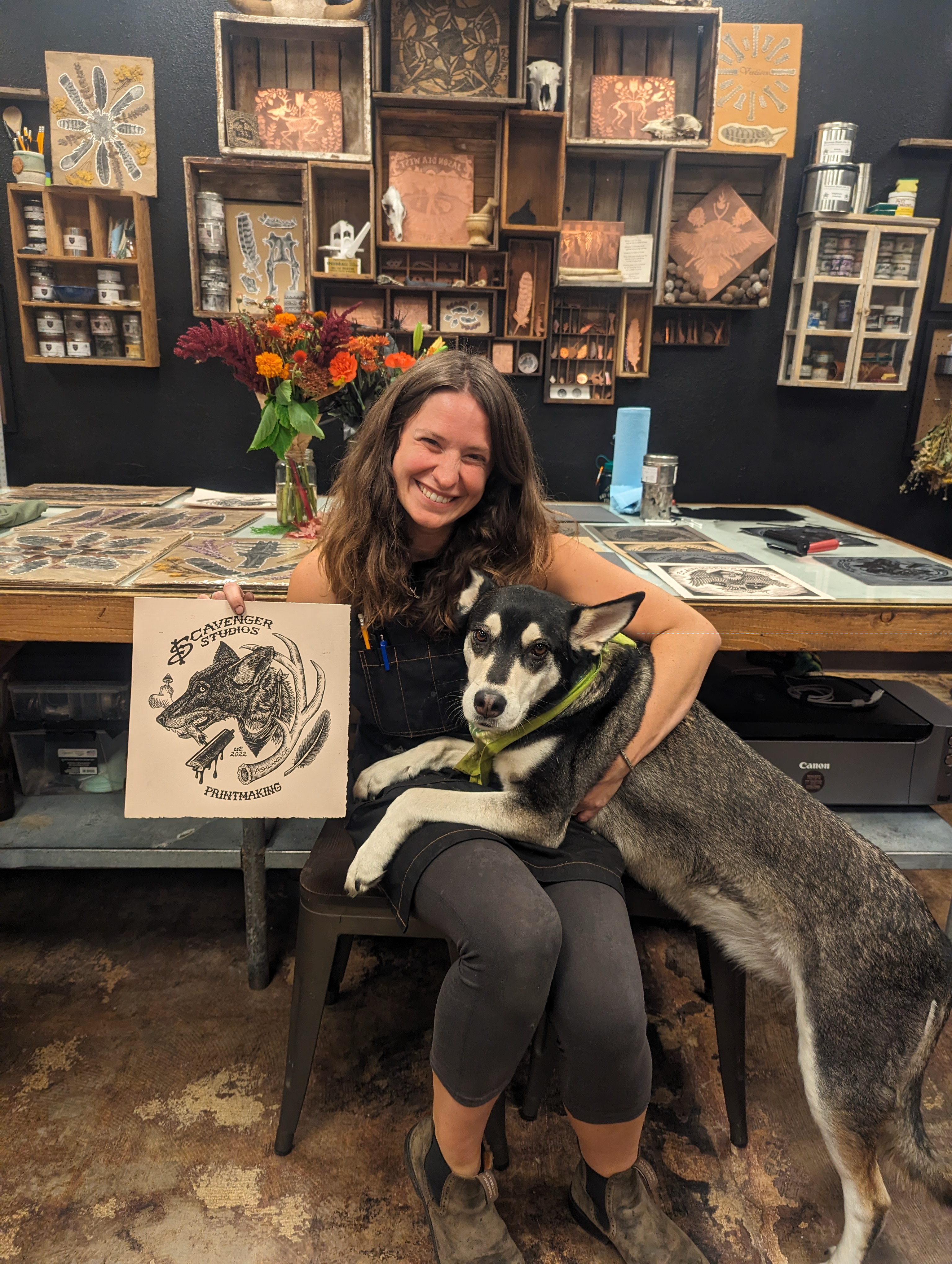 Image of Vanessa Jo Bahr with her dog and her art in her printmaking studio