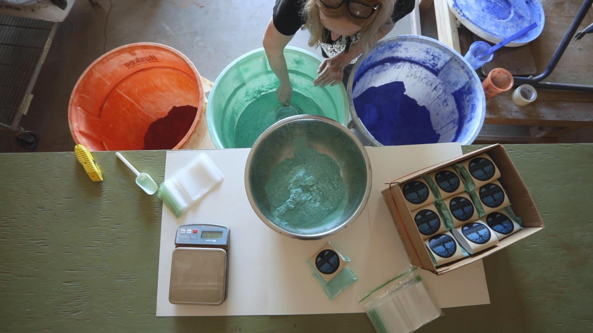 Bird's eye view of person scooping pigments and weighing into packages