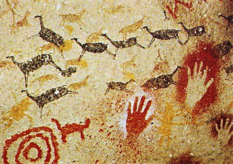 Close up image of a cave painting depicting 4-legged animals in brown, yellow and red along with stencils of people's hands in red and white