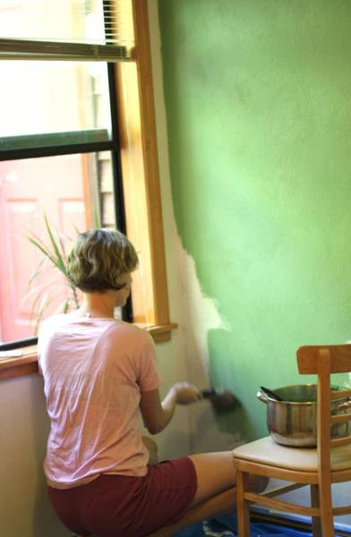 Image of person painting a wall green using a house paint recipe from Natural Earth Paint