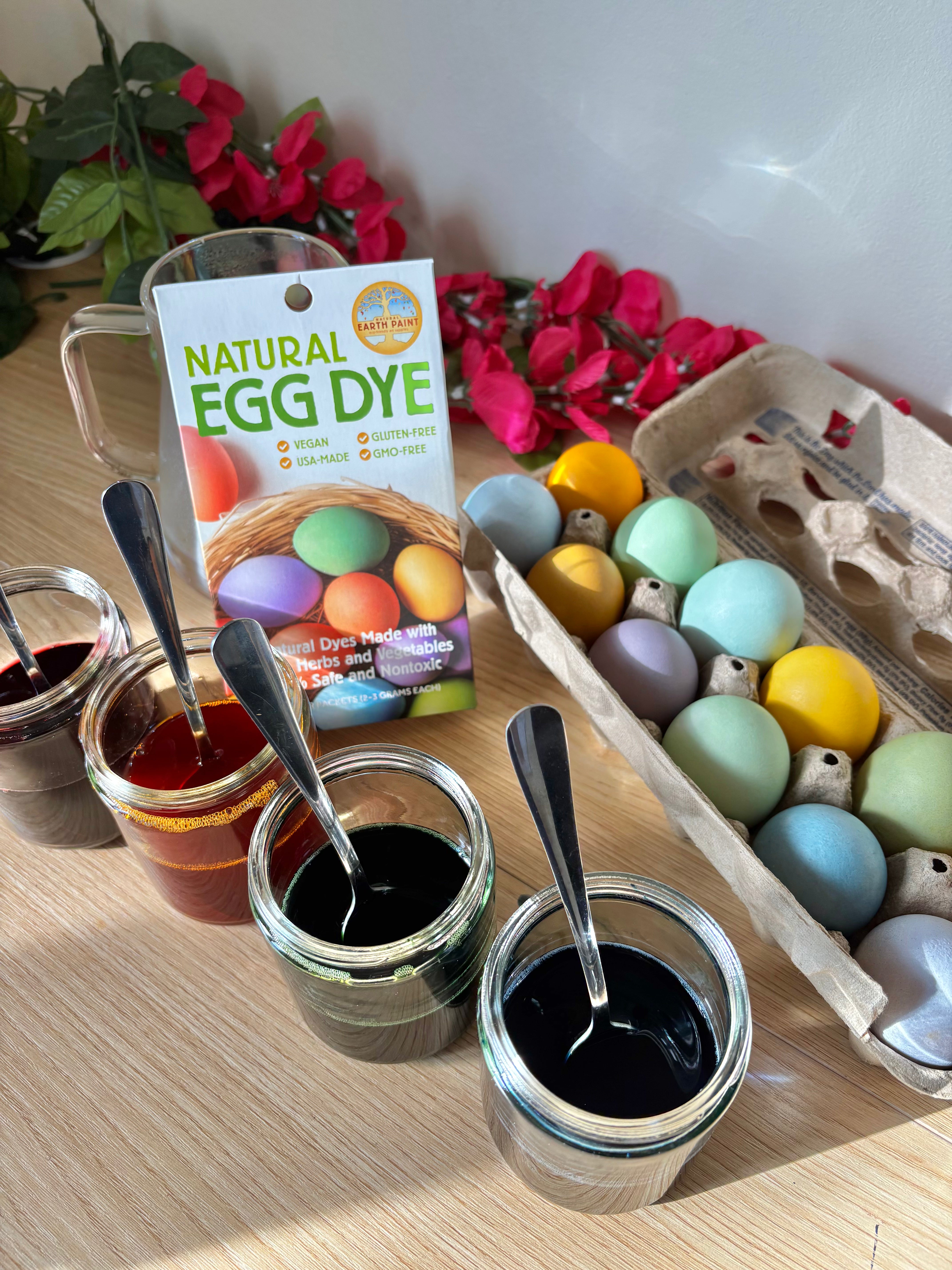 Egg dye in glass jars beside a tray of dyed eggs