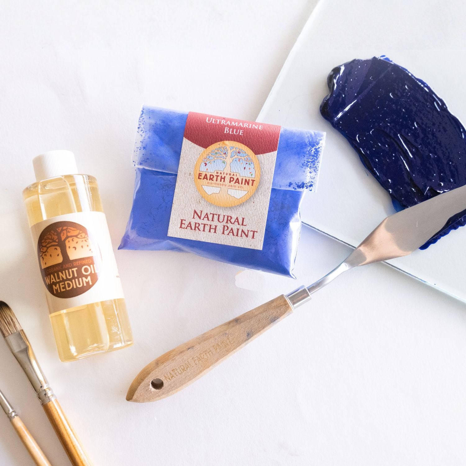 Bottle of walnut oil, pouch of ultramarine blue pigment, and the resulting glistening oil paint swatch 