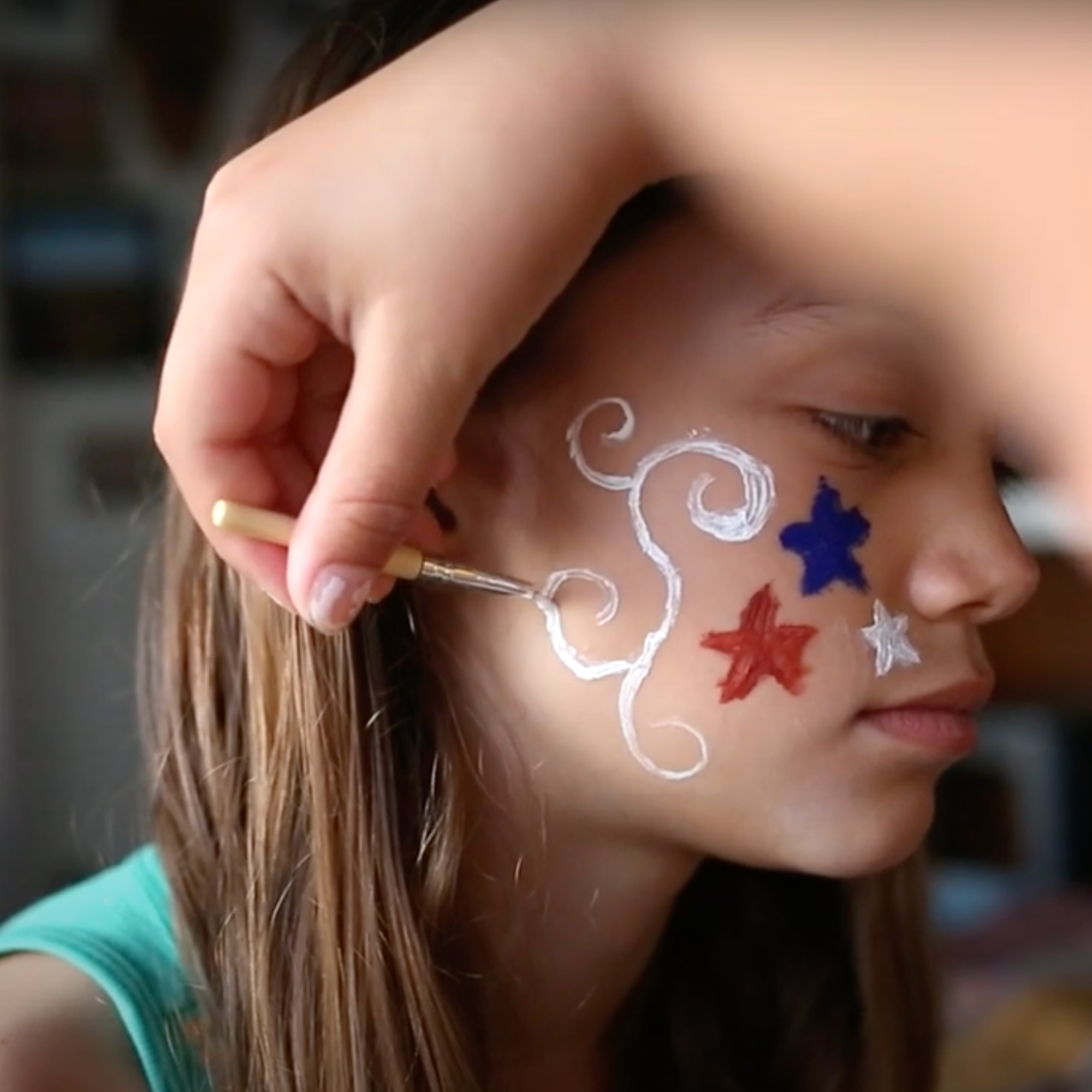 Girl getting her face painted with red, white, and blue stars