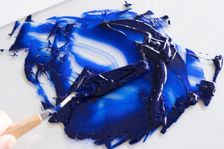 Blue paint and palette knife on a glass palette