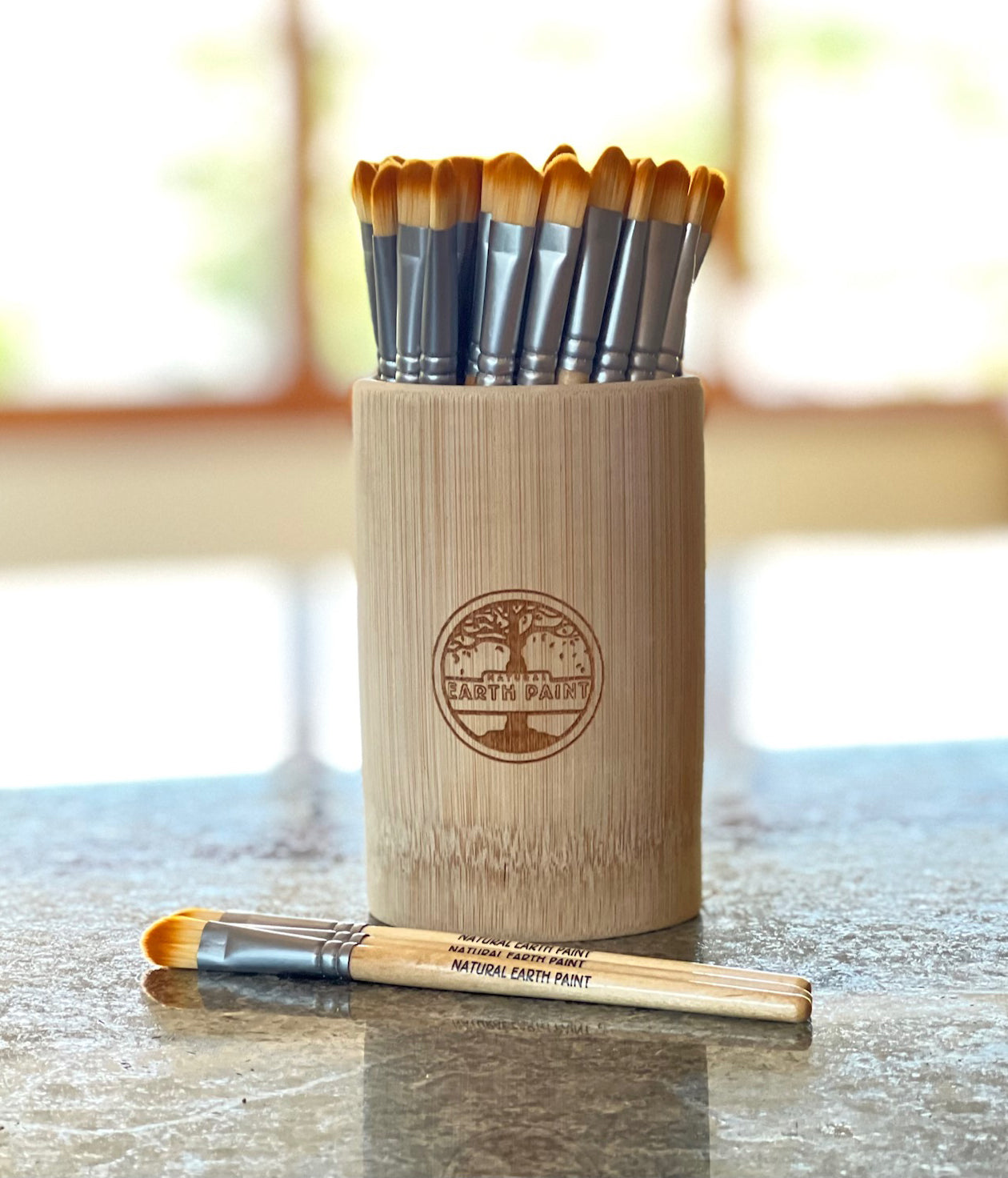 Branded bamboo cup holding thirty branded paint brushes