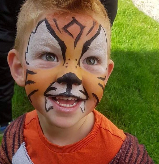 A small child whose face has been painted to resemble a tiger