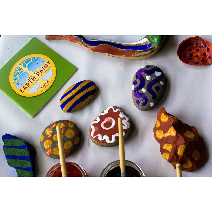 Samples of painted rocks, stones and wood with open jars of paint and instruction booklet