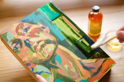 brushing varnish over painting of woman on canvas