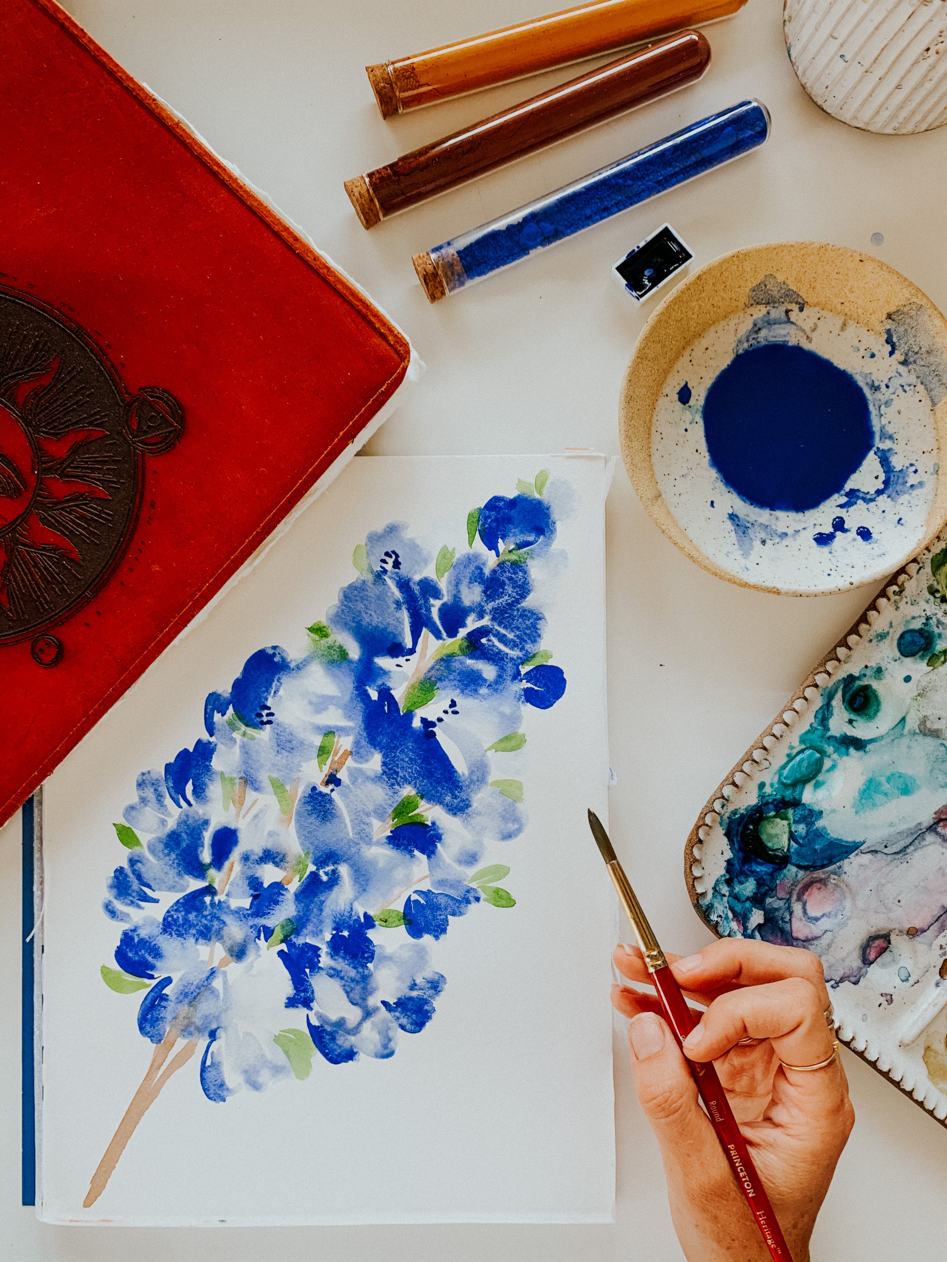 woman painting blue flower with watercolor