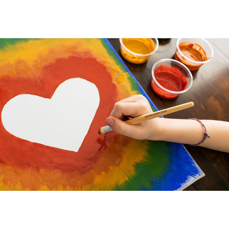 A child's hand painting a canvas with Natural Earth Paints