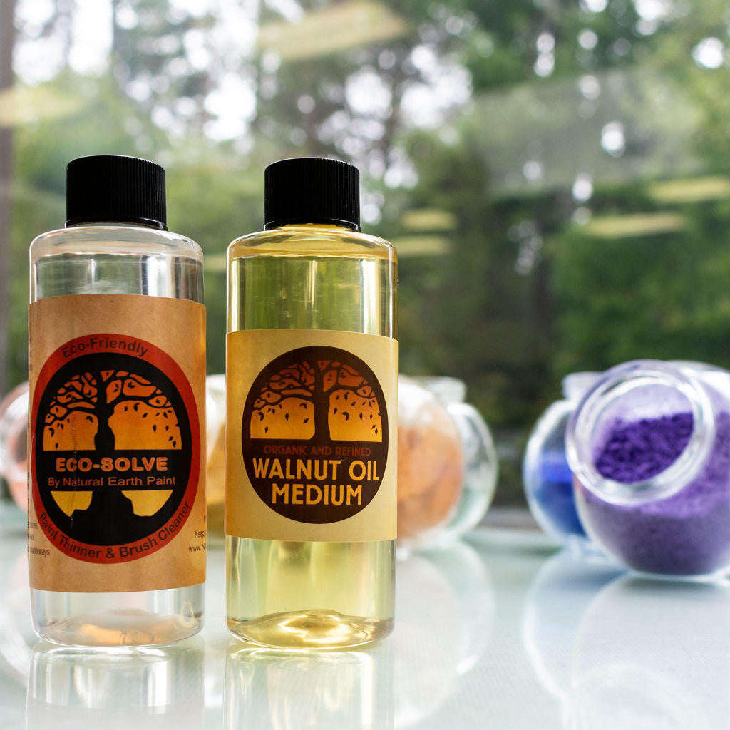 Four ounce bottles of walnut oil and Eco Solve with glass jars of pigment powders in the background